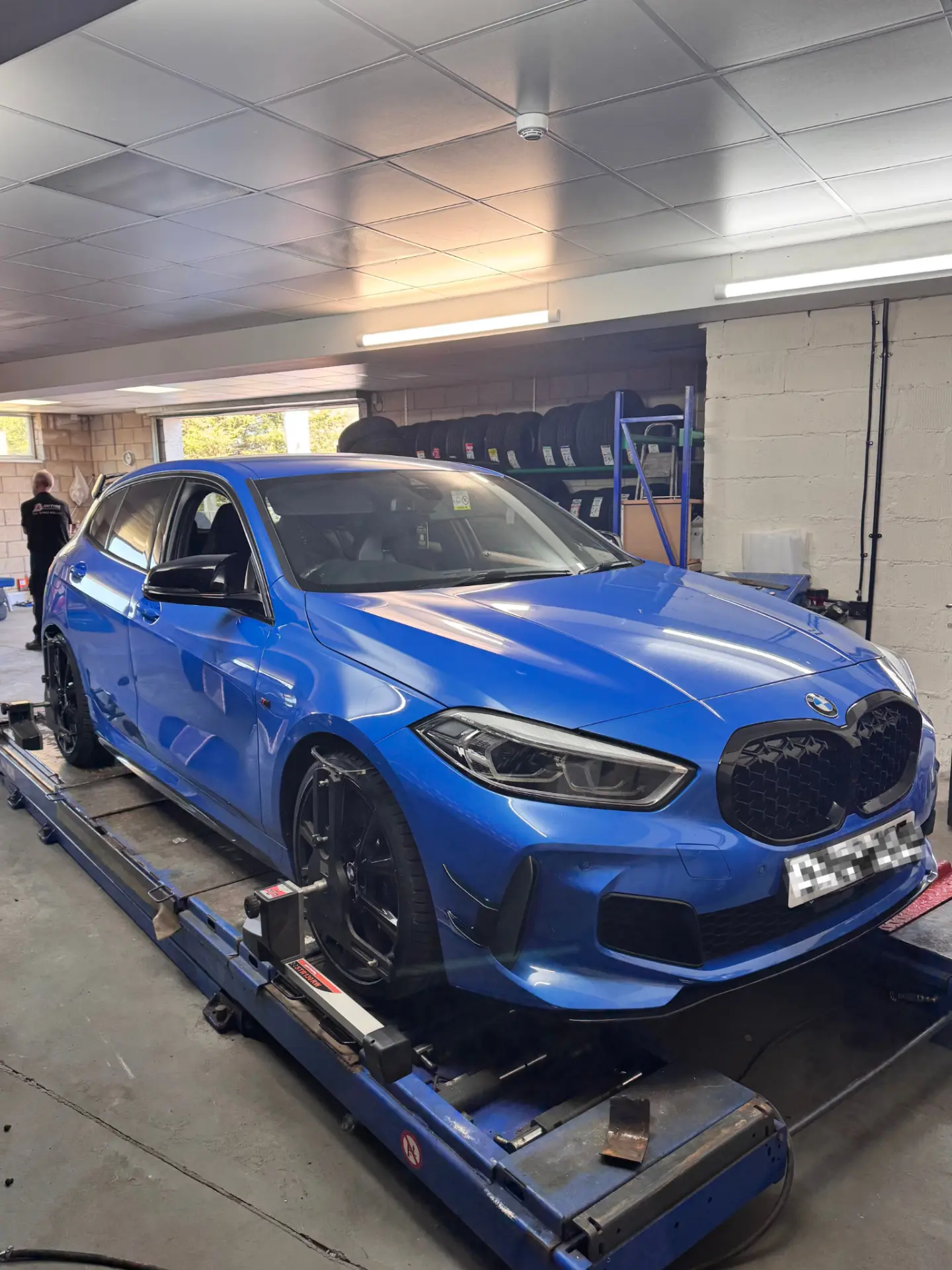Blue BMW on a 4-wheel alignment ramp at our Beoley workshop near Redditch